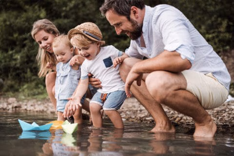 An image of a young family playing in a stream to represent family on the journey of life